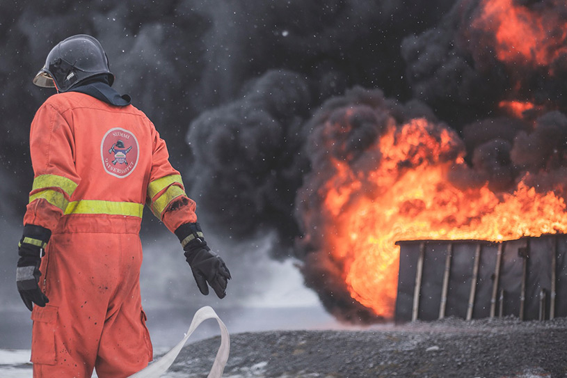 A photo of a fireman in front of a blaze.